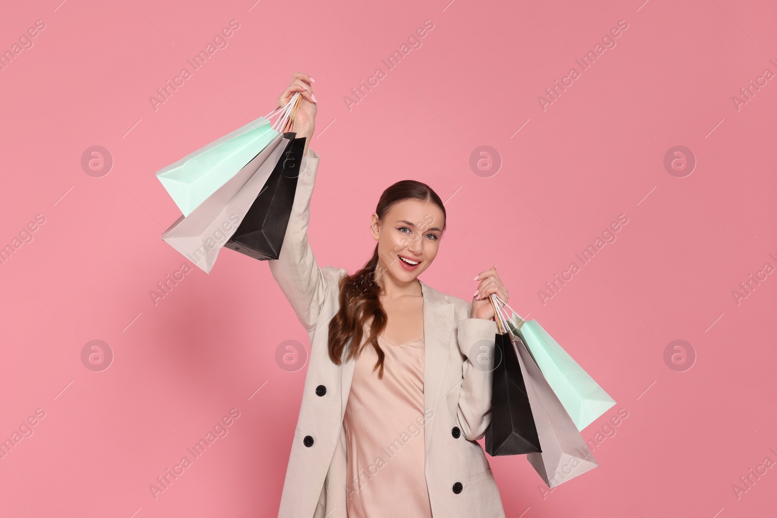 Photo of Stylish young woman with shopping bags on pink background