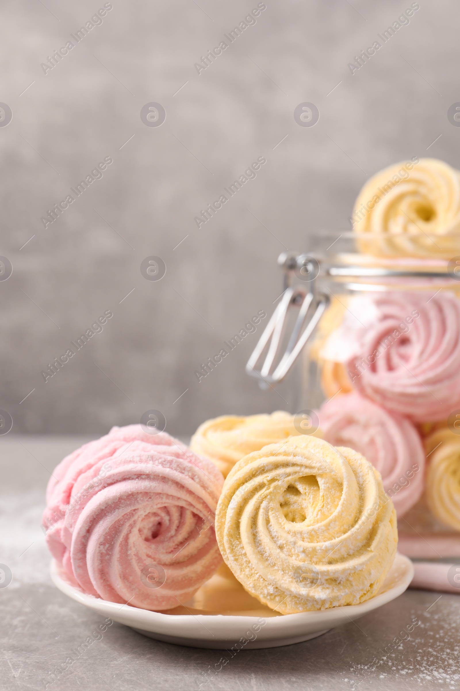 Photo of Delicious pink and yellow marshmallows on grey table