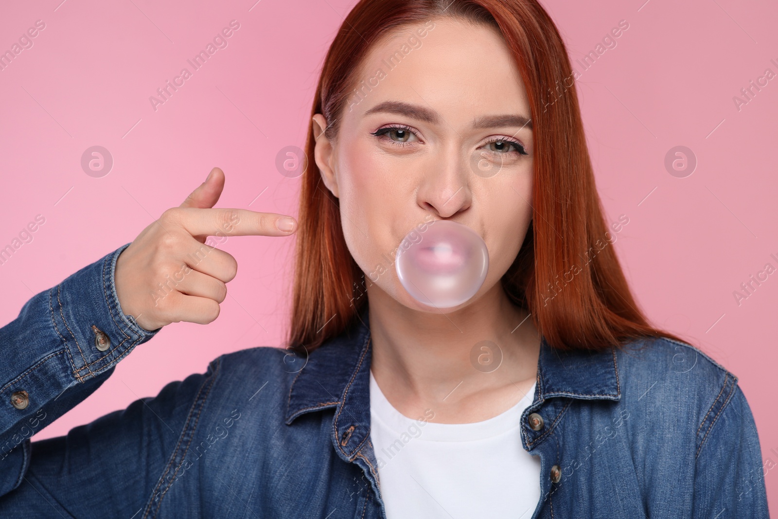 Photo of Portrait of beautiful woman blowing bubble gum on pink background