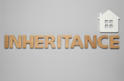 Word Inheritance made with wooden letters and house model on light background, flat lay