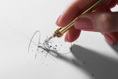 Photo of Woman signing on sheet of paper with fountain pen, closeup