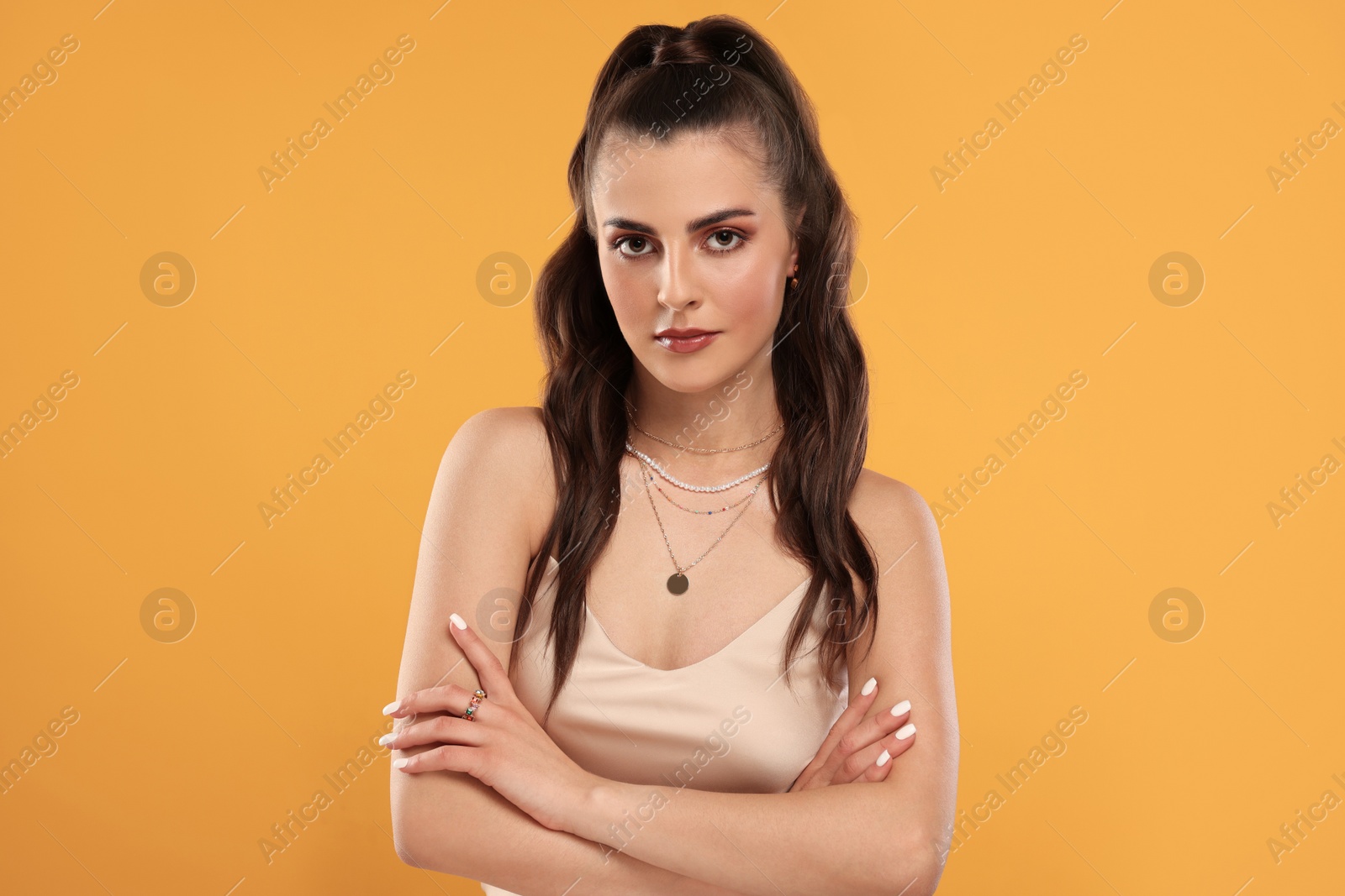 Photo of Beautiful woman with elegant jewelry on orange background