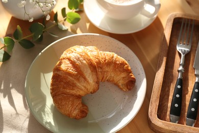 Photo of Tasty croissant served on wooden table, above view