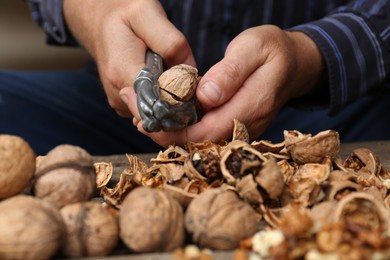 Man cracking walnuts at table, closeup view