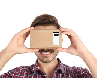 Young man using cardboard virtual reality headset, isolated on white