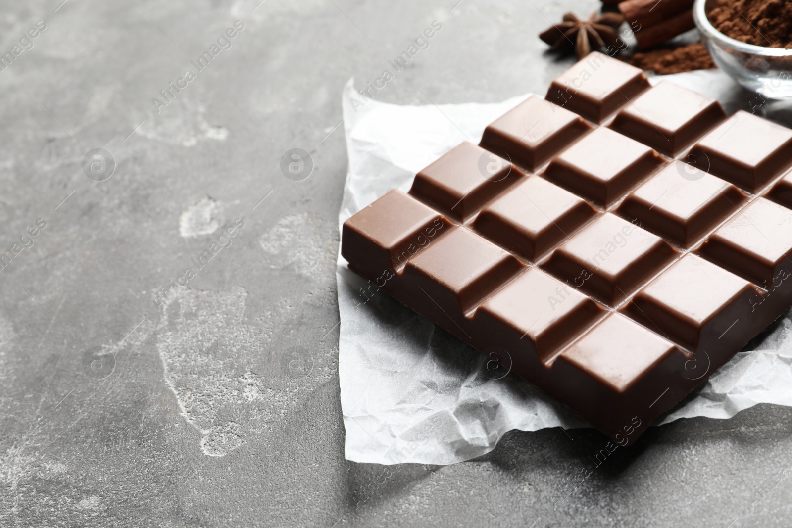 Photo of Chocolate bar and cocoa powder on grey background. Space for text