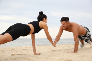 Couple doing exercise together on beach. Body training