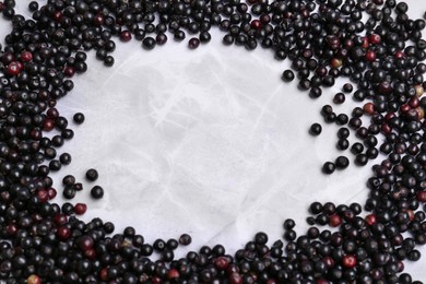 Frame of tasty elderberries (Sambucus) on white marble table, flat lay. Space for text