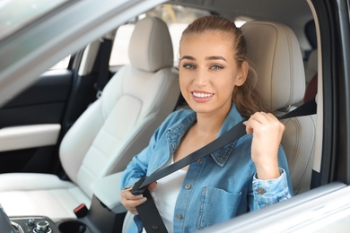 Female driver fastening safety belt in car