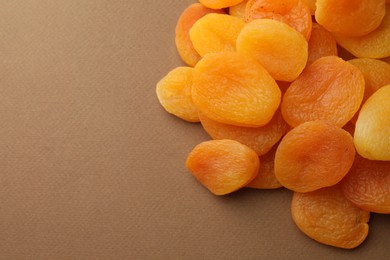 Many tasty dried apricots on pale brown, top view. Space for text