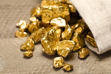 Overturned sack of gold nuggets on wooden table, closeup