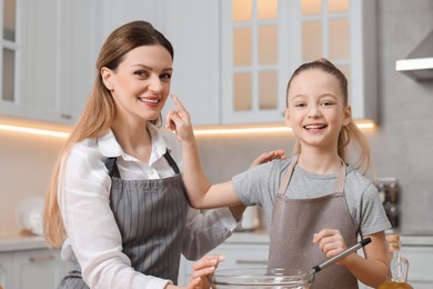 Making bread. Mother and her daughter preparing dough at wooden table in kitchen