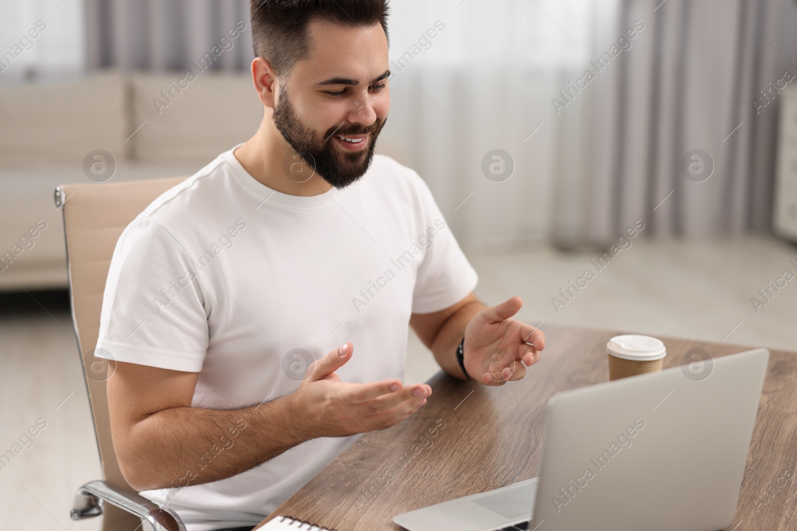 Photo of Young man using video chat during webinar at table in room