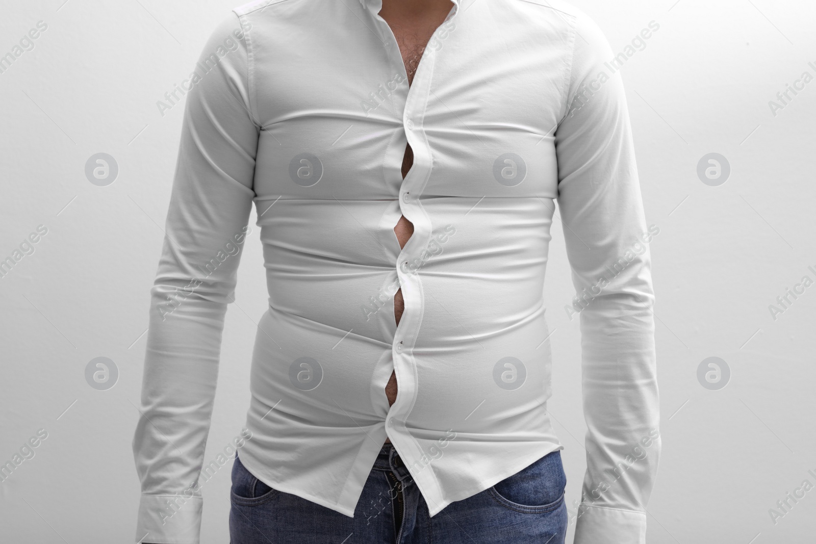 Photo of Man wearing tight shirt on white background, closeup. Overweight problem