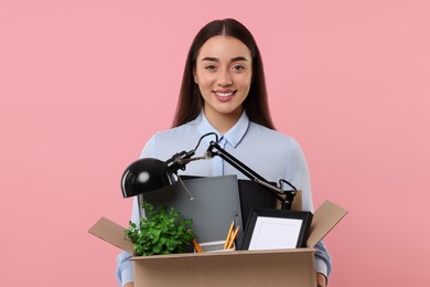 Photo of Happy unemployed woman holding box of personal office belongings on pink background