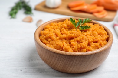 Photo of Bowl with mashed sweet potatoes on wooden table