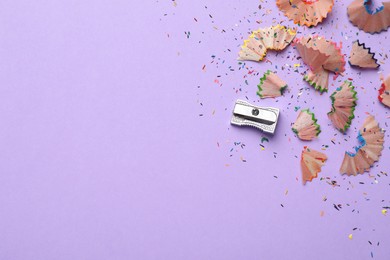 Photo of Pencil shavings and sharpener on violet background, flat lay. Space for text