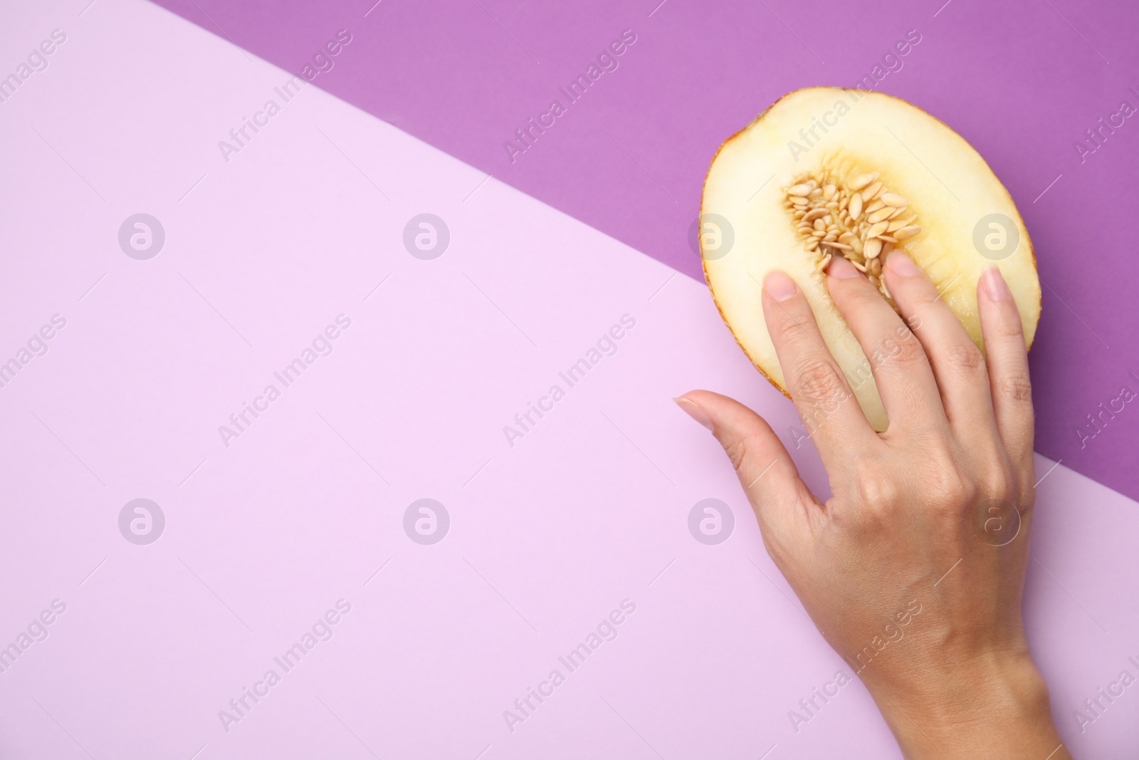 Photo of Young woman touching half of melon on color background, above view with space for text. Sex concept