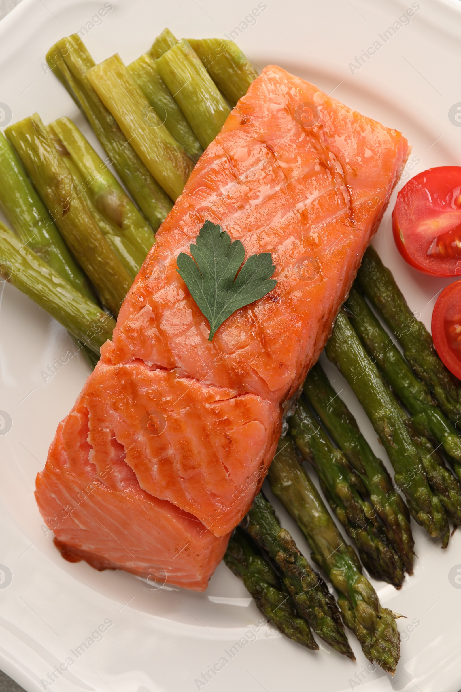 Photo of Plate with tasty grilled salmon, tomatoes and asparagus, top view