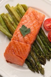 Photo of Plate with tasty grilled salmon, tomatoes and asparagus, top view