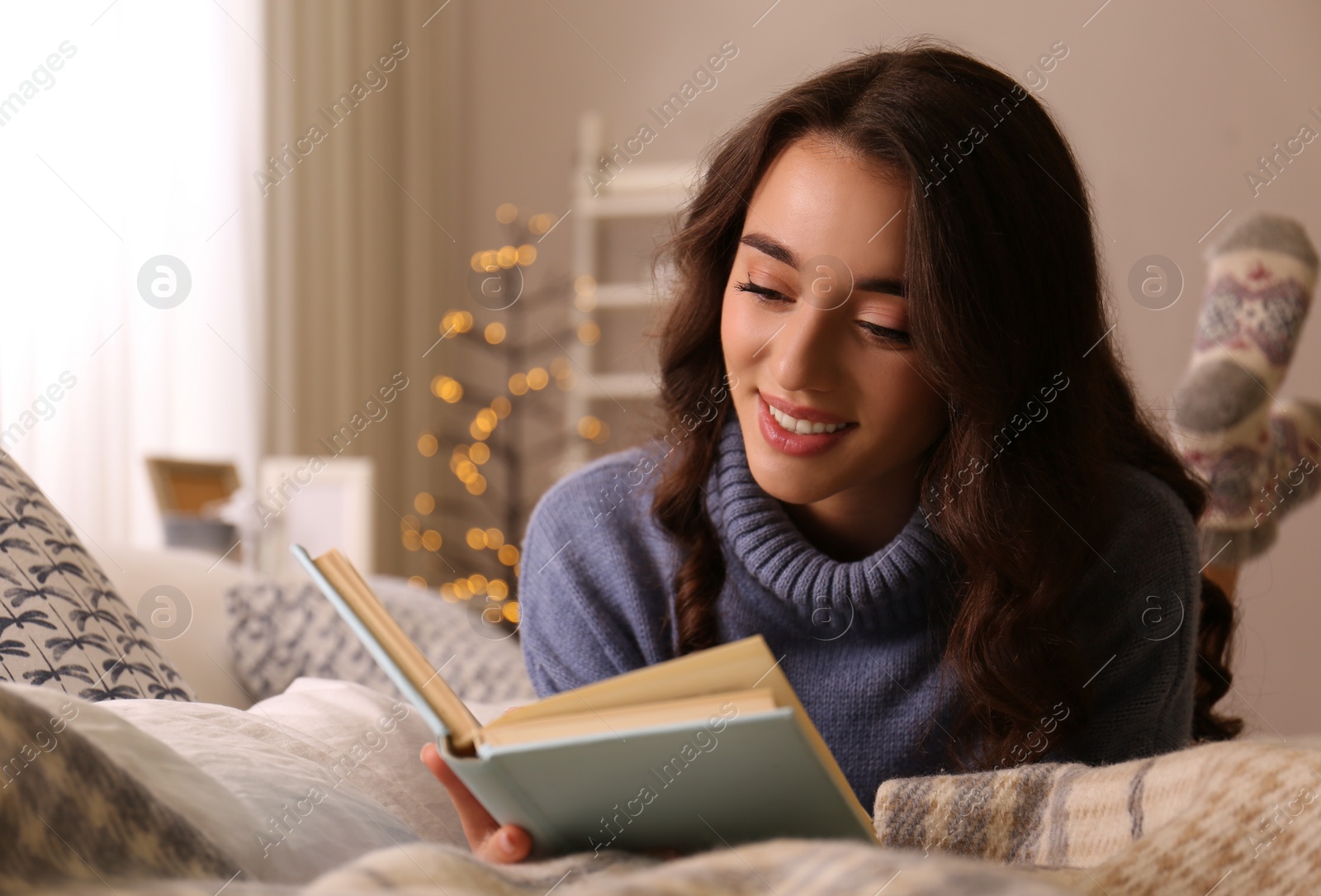 Photo of Young woman reading book at home. Winter atmosphere