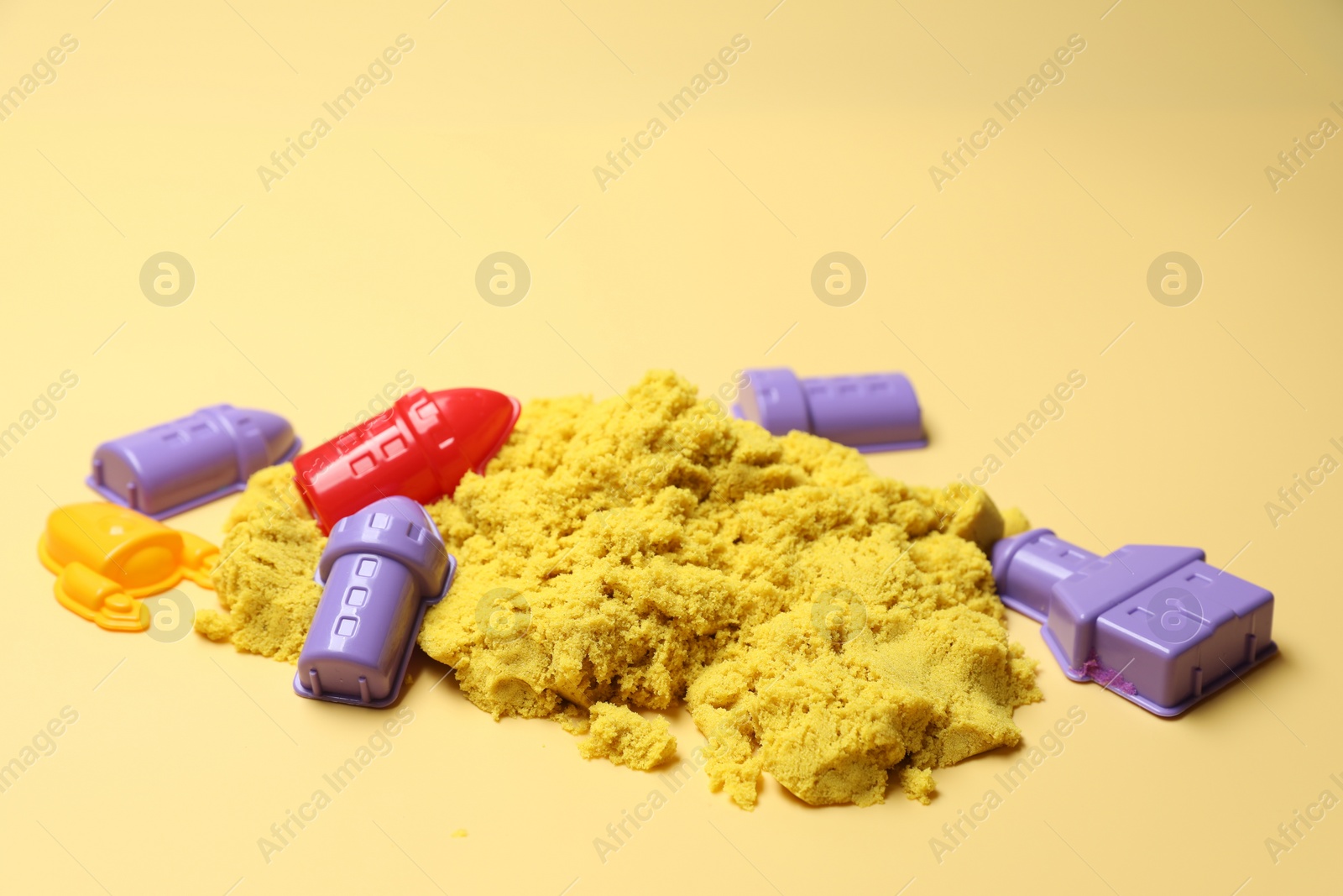 Photo of Bright kinetic sand and plastic toys on beige background