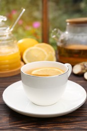 Cup of delicious tea with lemon and honey on wooden table