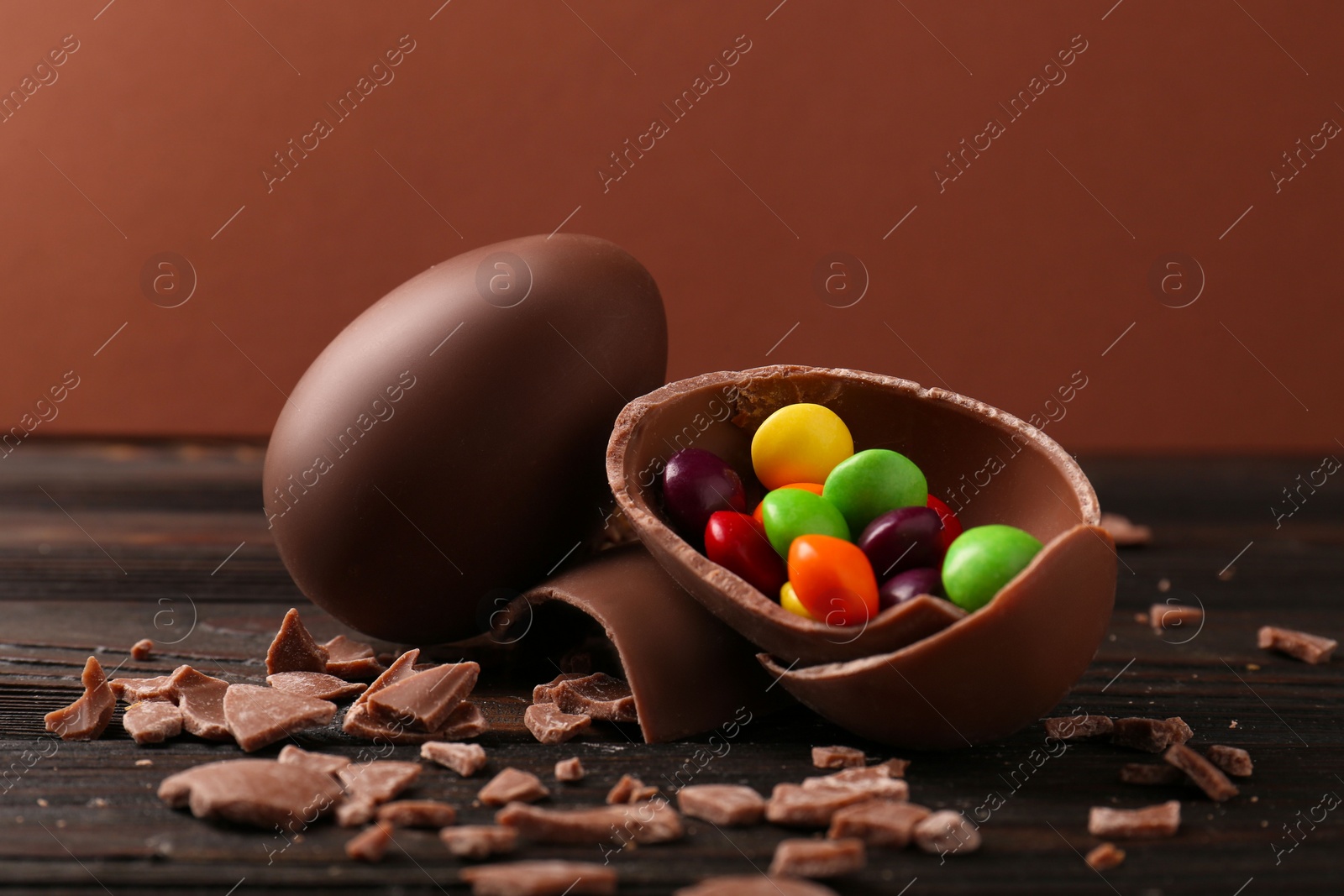 Photo of Broken and whole chocolate eggs with sweets on wooden table