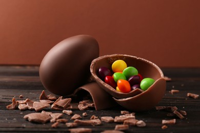 Broken and whole chocolate eggs with sweets on wooden table