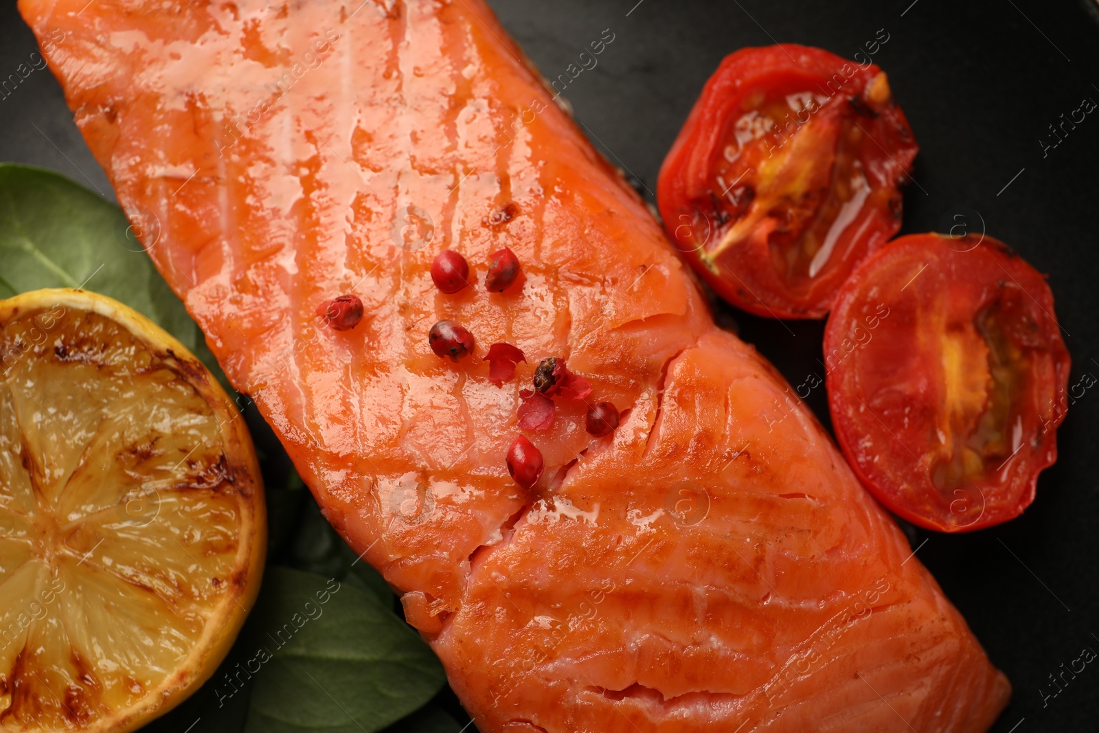 Photo of Plate with tasty grilled salmon, tomatoes, lemon and basil, top view