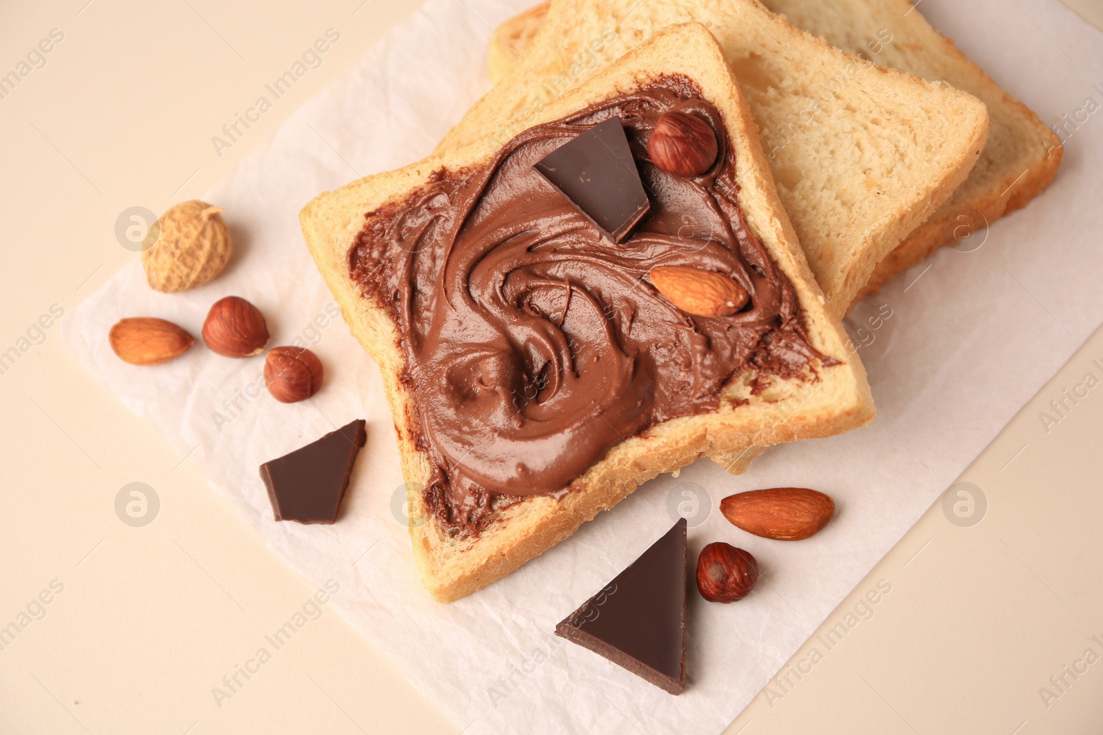 Photo of Tasty toast with chocolate paste and nuts on light background