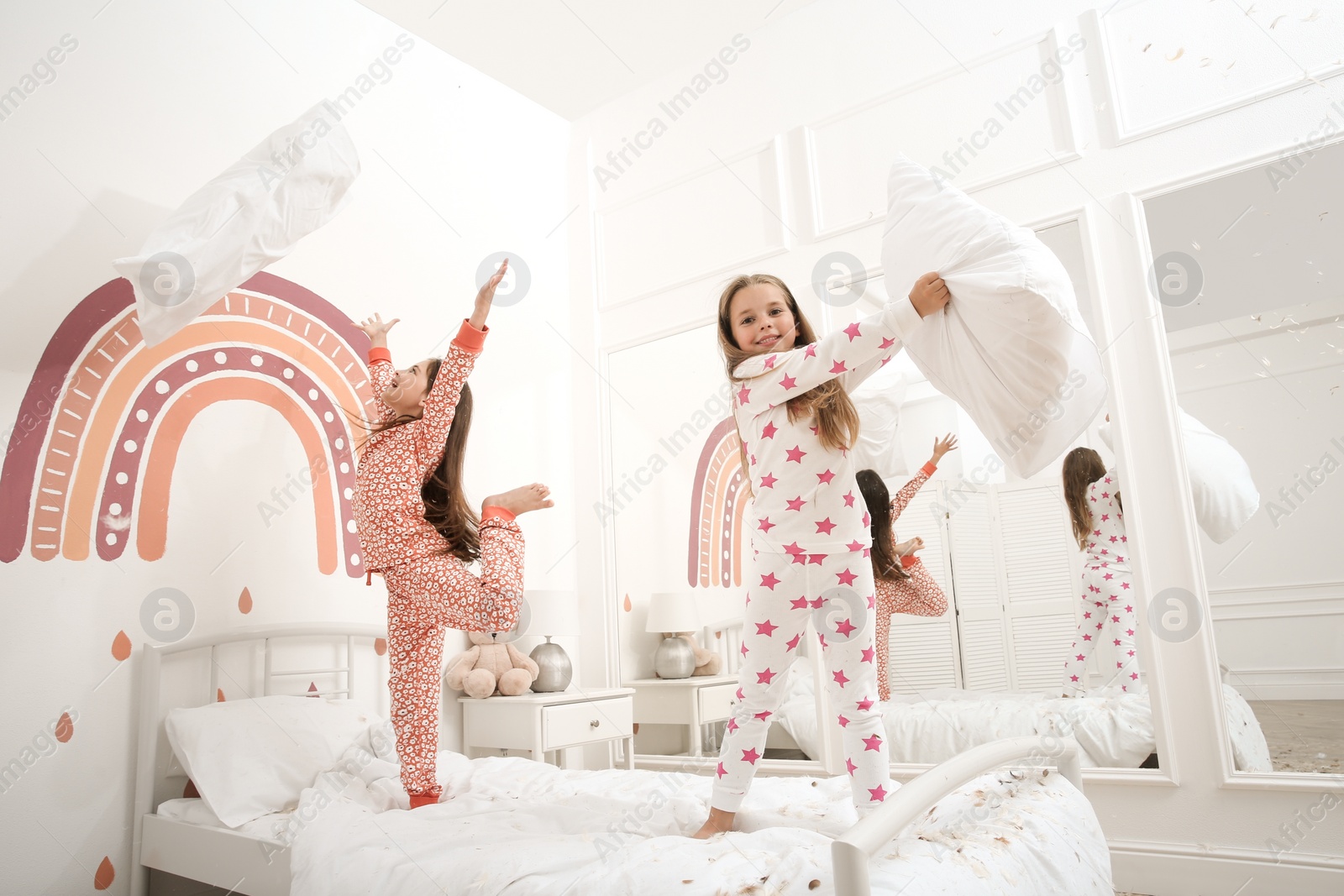 Photo of Cute little girls in pajamas playing on bed at home. Happy childhood