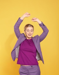 Happy young businesswoman celebrating victory on color background
