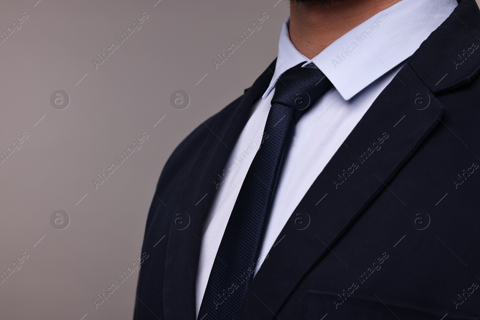 Photo of Businessman in suit and necktie on grey background, closeup. Space for text