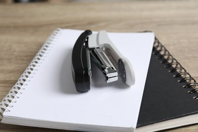 Stapler and notebooks on table, closeup view