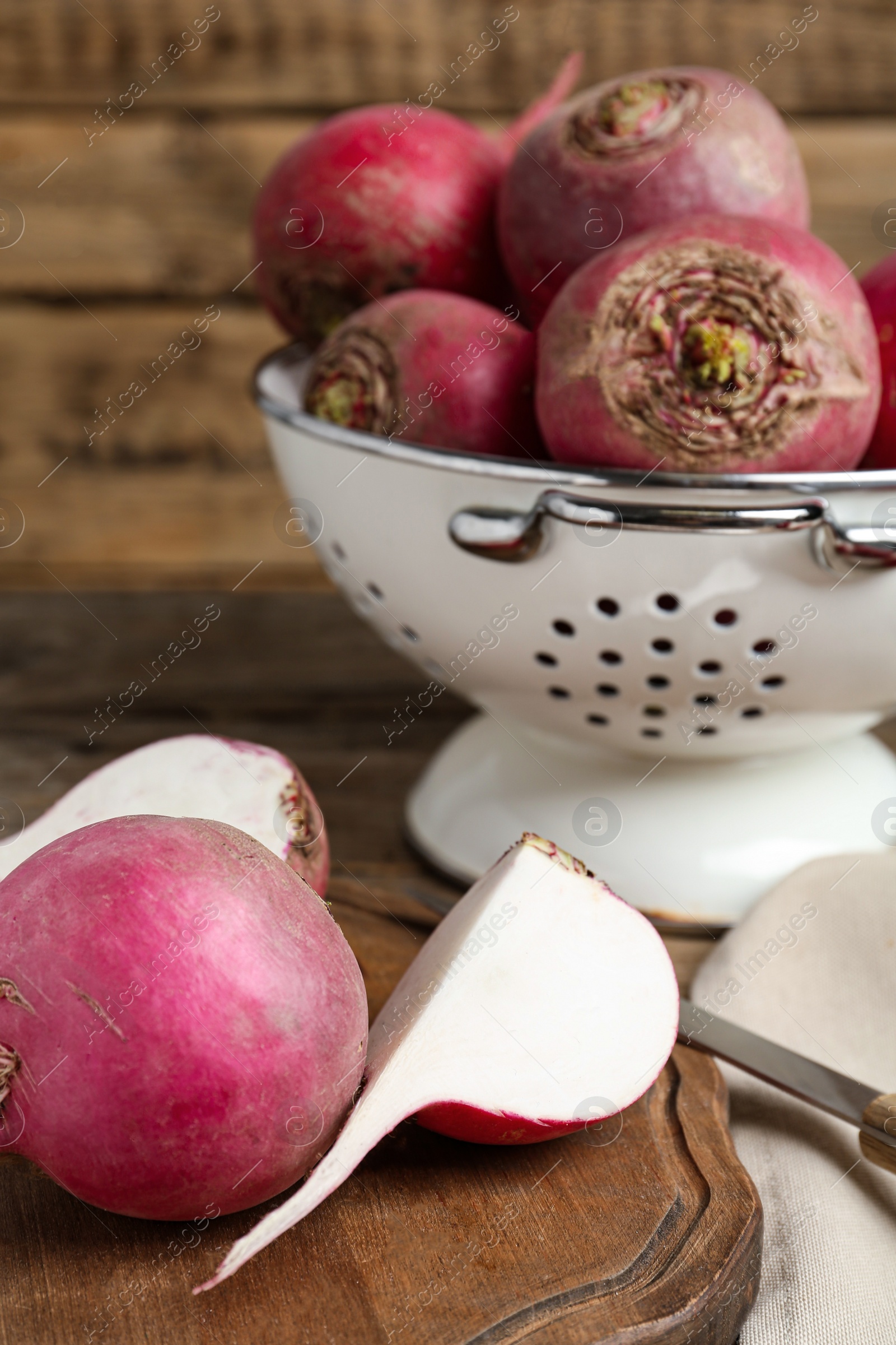 Photo of Cut and whole red turnips on wooden board, closeup