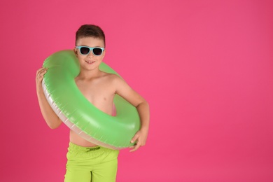 Photo of Cute little child in beachwear with bright inflatable ring on pink background. Space for text