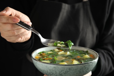Photo of Woman eating delicious sorrel soup in ceramic bowl, closeup