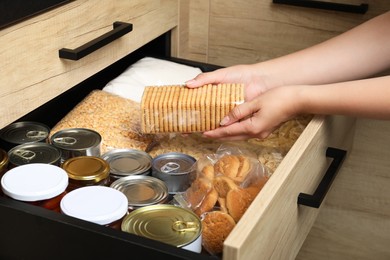 Woman taking food out from open drawer indoors, closeup
