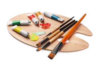 Photo of Wooden palette with oil paints and brushes on white background