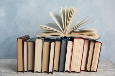 Stack of hardcover books on wooden table against light blue background