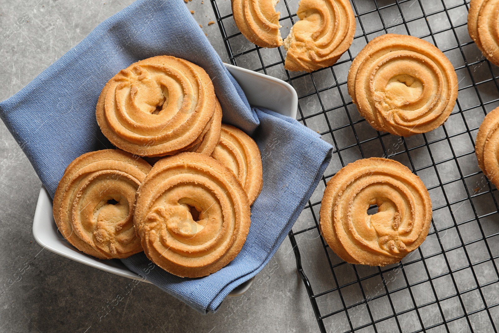 Photo of Bowl and baking rack with Danish butter cookies on grey table, top view