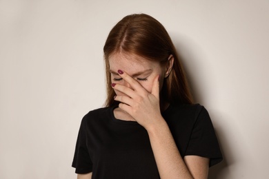Photo of Young woman covering face against light background