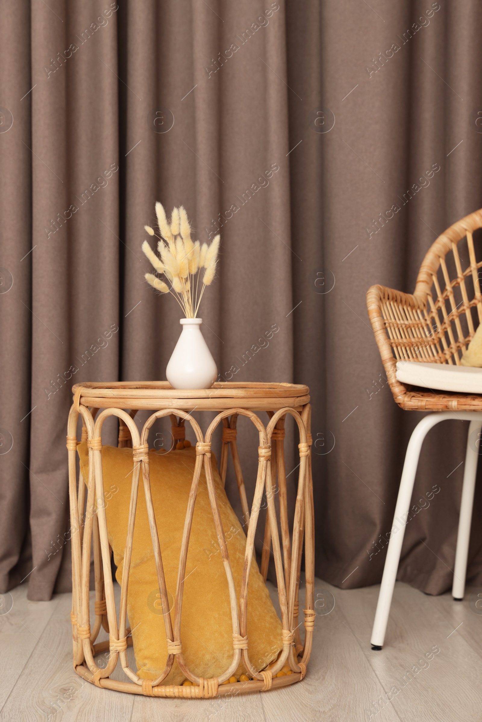 Photo of Armchair and wicker table with vase near elegant curtains indoors