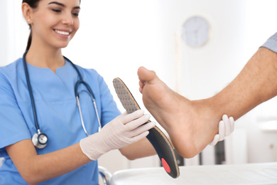 Photo of Female orthopedist fitting insole on patient's foot in clinic
