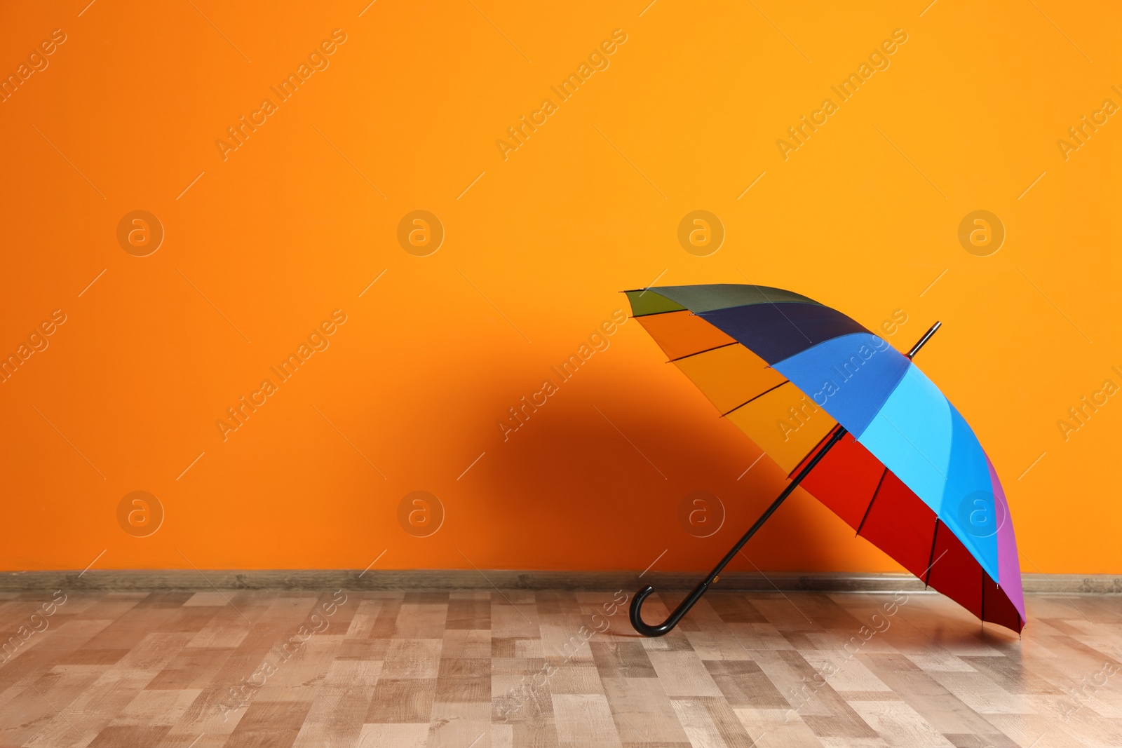 Photo of Beautiful open umbrella on floor near color wall with space for design