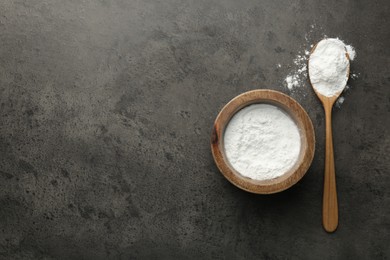 Photo of Baking powder in bowl and spoon on grey textured table, top view. Space for text