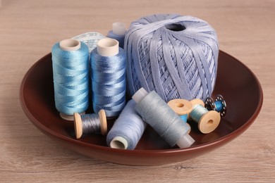 Photo of Color sewing threads in bowl on wooden table