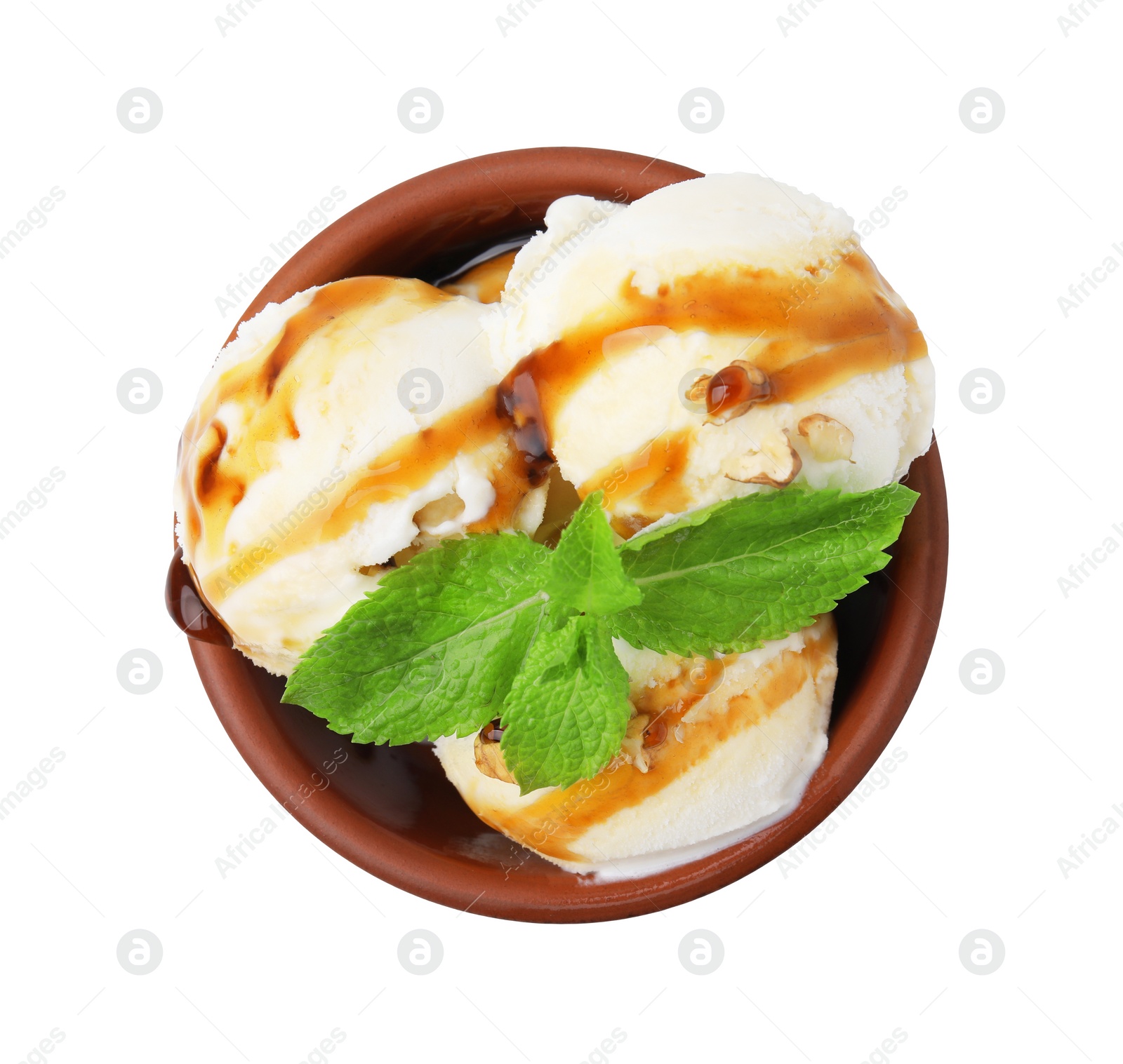 Photo of Tasty ice cream with caramel sauce, mint and nuts in bowl isolated on white, top view