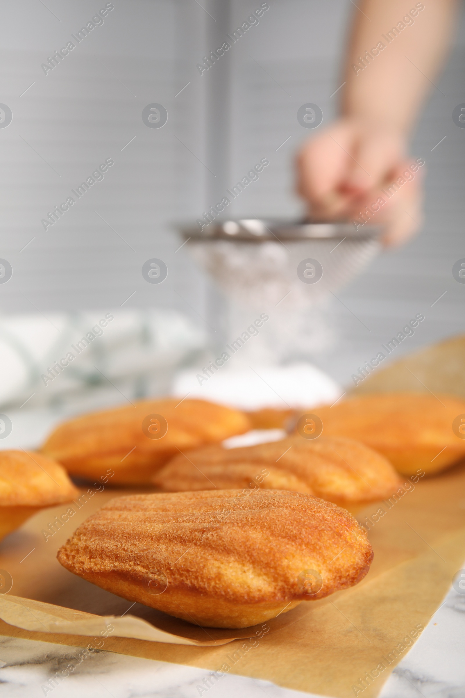 Photo of Delicious madeleine cakes on white marble table, closeup